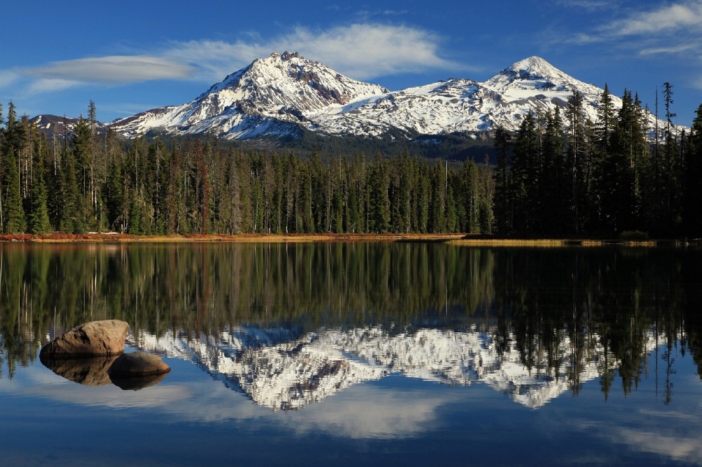 Snow-peaked mountains reflect into the pristine, still waters of Scott Lake deep within the Willamette National Forest.